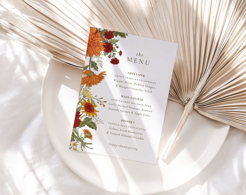 Pu&ograve; includere: Un menu del Ringraziamento con un design floreale con fiori arancioni, rossi e gialli. Il menu include opzioni di antipasti, piatti principali e dessert. Il testo recita "the MENU", "APPETIZER", "CRISPY TEMPURA VEGETABLES", "Wasabi Mayo, Pickled Ginger, & Mango-Coriander Salad", "MAIN COURSE", "SLOW COOKED BOURBON PORK", "Garlic Mashed Potatoes, Roasted Brussels Sprouts & Apple Cider", "DESSERT", "VANILLA BEAN PANNACOTTA", "Gelato, Fresh Blueberries & Toasted Almond Crumble", "happy thanksgiving".
