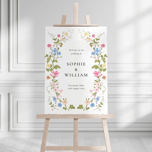 May include: A white wedding welcome sign with a floral border. The sign reads "Welcome to the wedding of Sophie & William, Cleveland, Ohio, 14th August 2023".