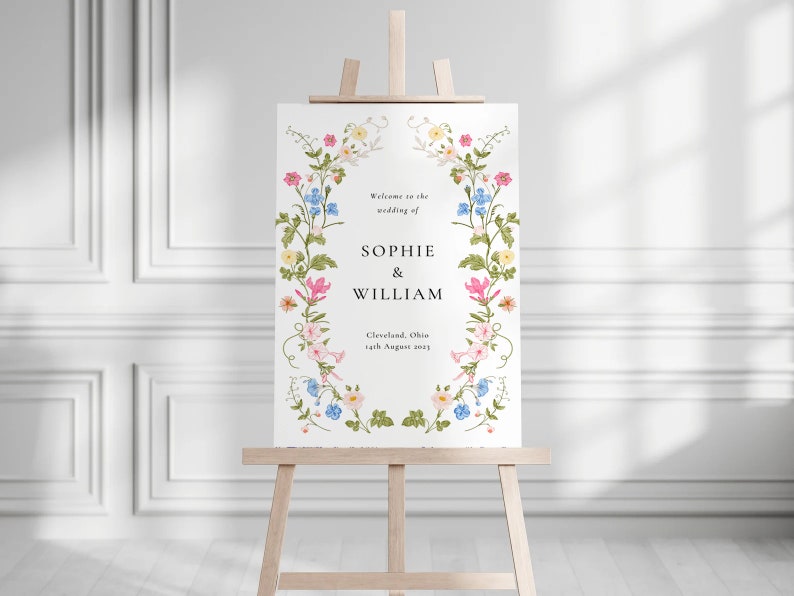 May include: A white wedding welcome sign with a floral border. The sign reads "Welcome to the wedding of Sophie & William, Cleveland, Ohio, 14th August 2023".