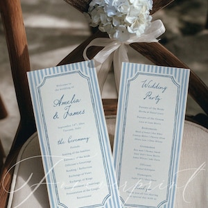 以下が含まれることがあります： 青と白のストライプの縁取りが施された結婚式のプログラム。 「Amelia & James」と「Wedding Party」の名前が記載されています。 花の装飾が椅子を飾っています。 プログラムには、式典の詳細と結婚式のメンバーが記載されています。