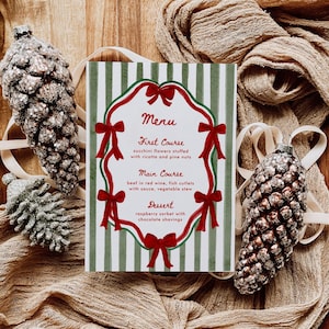 Puede incluir: Una tarjeta de menú festiva con un fondo a rayas verdes y blancas, lazos rojos y un borde decorativo. El menú enumera tres platos: flores de calabacín, ternera al vino tinto y sorbete de frambuesa. Dos adornos decorativos de piñas a cada lado.