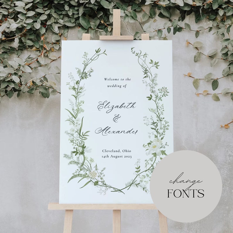Pode incluir: Um cartaz de casamento branco com uma borda de coroa de flores. O cartaz diz "Bem-vindos ao casamento de Elizabeth & Alexander" e inclui a data e o local: "Cleveland, Ohio 14 de agosto de 2023".
