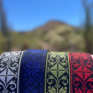 Peut inclure: Quatre sangles de guitare tiss&eacute;es avec des motifs de couleurs diff&eacute;rentes. Les sangles sont noires avec des motifs blancs, bleus, verts et rouges.