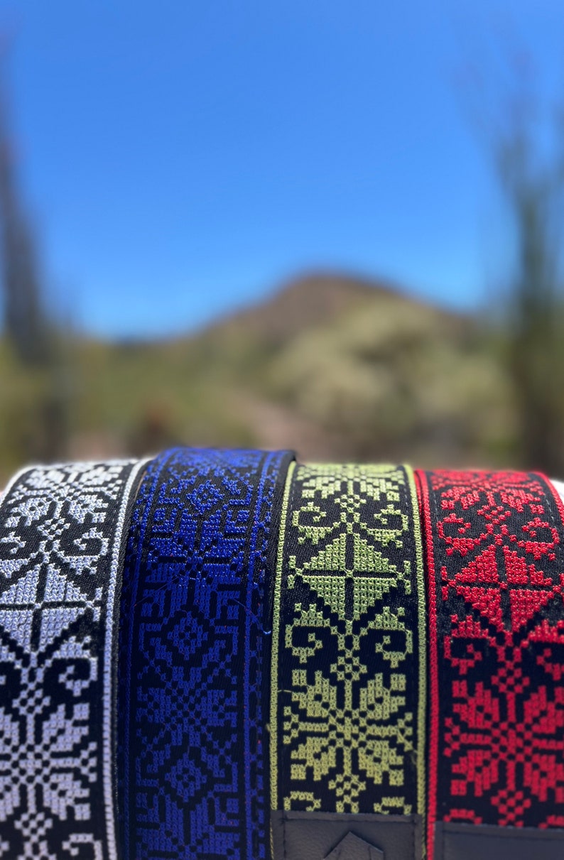 Peut inclure: Quatre sangles de guitare tiss&eacute;es avec des motifs de couleurs diff&eacute;rentes. Les sangles sont noires avec des motifs blancs, bleus, verts et rouges.
