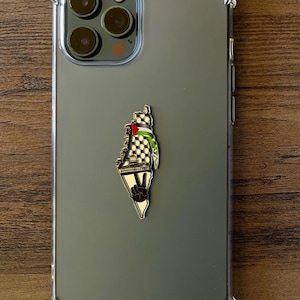 May include: A clear phone case with a black and white outline of Palestine with a peace sign and the Palestinian flag on a green background.