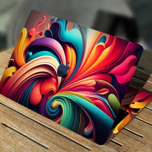 Könnte beinhalten: Ein Laptop mit einem farbenfrohen abstrakten Design auf der Abdeckung. Das Design zeigt wirbelnde, überlappende Formen in Rot-, Orange-, Gelb-, Grün-, Blau- und Violetttönen.