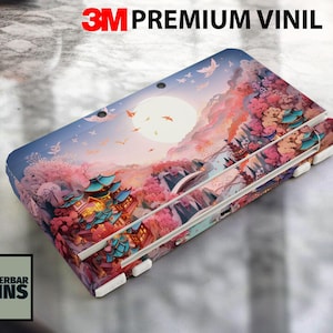 Puede incluir: Una funda para dispositivo con un paisaje vibrante de pagodas, flores de cerezo y una luna llena. El diseño incorpora tonos de rosa, azul y naranja. El texto "3M PREMIUM VINIL" está en la parte superior y el logo "WUNDERBAR SKINS" en la esquina inferior izquierda.