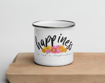 May include: White enamel mug with a black and white graphic that says "happiness is not a destination" with a floral design of pink, yellow, and orange flowers.