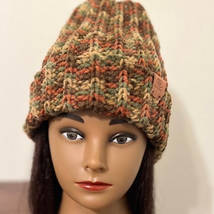 May include: A brown, green, and orange knitted beanie with a brown leather patch that says "Knit Wit".