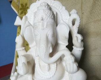 Op de afbeelding: Een witte marmeren sculptuur van de hindoeïstische god Ganesha. De sculptuur toont Ganesha zittend, met meerdere armen, een olifantenkop en ingewikkelde details. Het beeld heeft een serene uitdrukking en is versierd met sieraden.