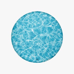 Puede incluir: Un PopSocket redondo azul con un diseño de ondas de agua. La imagen muestra un primer plano del PopSocket, con el efecto del agua en tonos azules y blancos. Las iniciales "OB" son visibles en la esquina inferior derecha.
