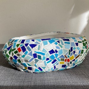 May include: A white ceramic planter with a mosaic design. The mosaic is made of small, colourful tiles in shades of blue, green, red, and yellow.