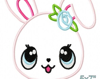 May include: Embroidered design of a cute cartoon bunny with big eyes, a pink nose, and a pink flower on its head. The bunny is sitting with its legs crossed and has a small blue heart on its chest. The design is available in three sizes: 5x7 inches, 6x10 inches, and 7x11 inches.