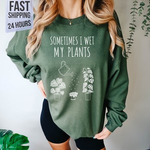 May include: Green sweatshirt with the text "Sometimes I Wet My Plants" and a graphic of a watering can and three potted plants.