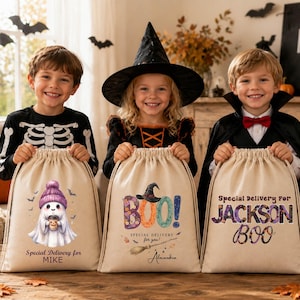 May include: Three beige canvas drawstring bags for Halloween. The left bag features a ghost in a purple hat with the text Special Delivery for MIKE. The center bag shows the word BOO! with a witch hat and broom, and the text Alexandra. The right bag displays the text Special Delivery for JACKSON BOO.