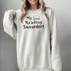 May include: A white sweatshirt with the text "My Reading Sweatshirt" and an illustration of an open book.