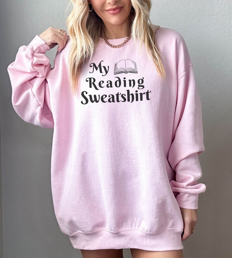 May include: A pink sweatshirt with the text "My Reading Sweatshirt" and a black and white illustration of an open book.