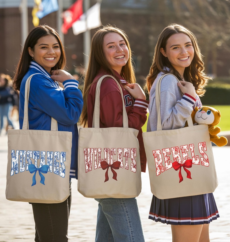 Three young women standing together, each carrying a tote bag with a red ribbon and the word "Wildcats" printed on it.