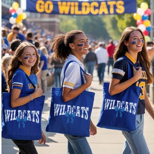 Three young women wearing blue and yellow "Wildcats" shirts and carrying blue bags with the same "Wildcats" text are walking together, smiling and enjoying the event.