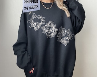 May include: Black sweatshirt with a white graphic of three skulls surrounded by flowers.