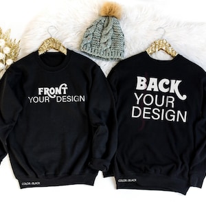 May include: Two black crewneck sweatshirts with long sleeves and ribbed cuffs. The left sweatshirt features white text reading FRONT YOUR DESIGN, while the right sweatshirt displays white text reading BACK YOUR DESIGN. A gray knit beanie sits above.