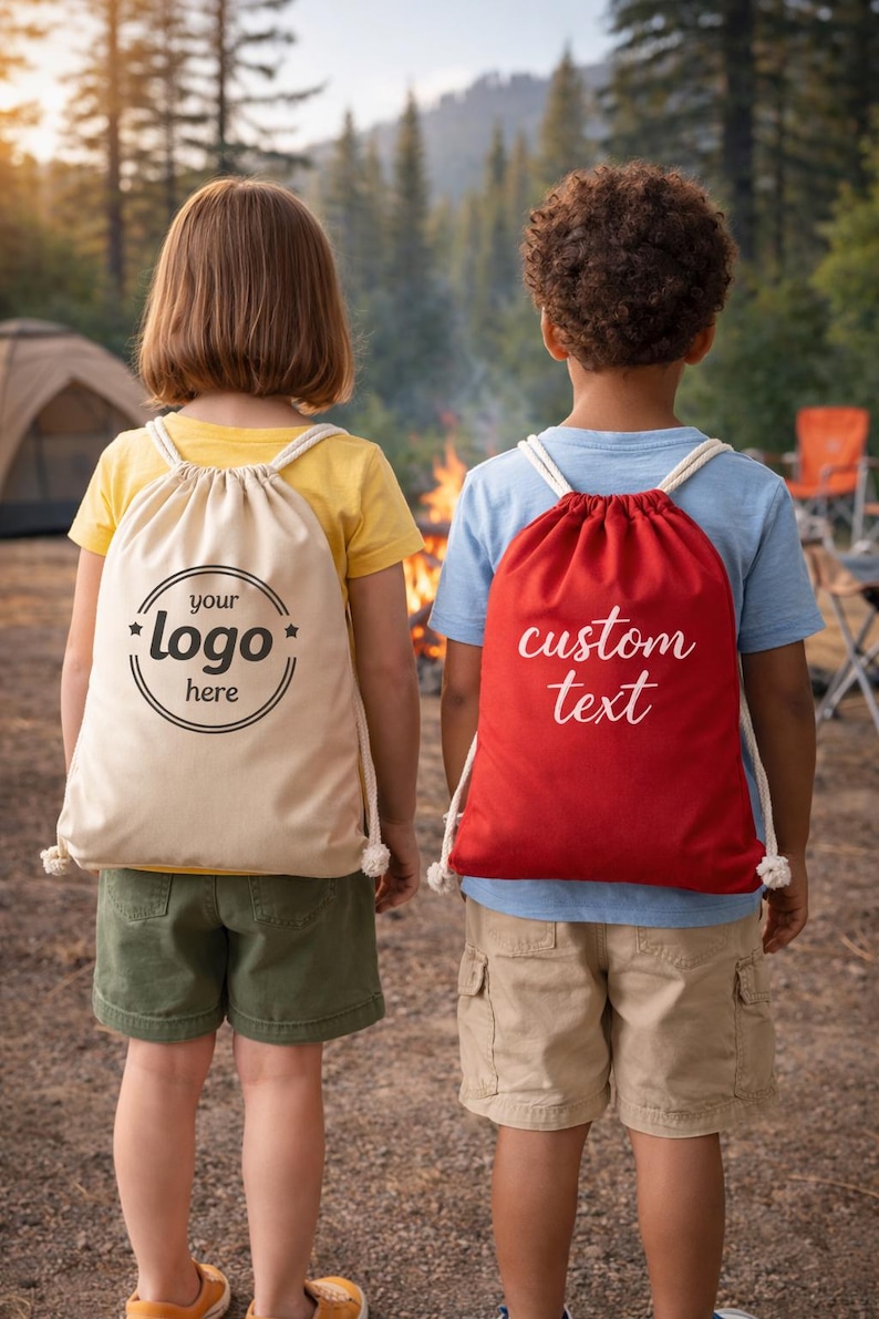 Two children standing in front of a campfire, each carrying a bag with custom text printed on it.