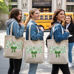 Three young women standing on a sidewalk, each carrying a beige tote bag with the word "SEARS" printed on it. They are smiling and appear to be enjoying their time together.