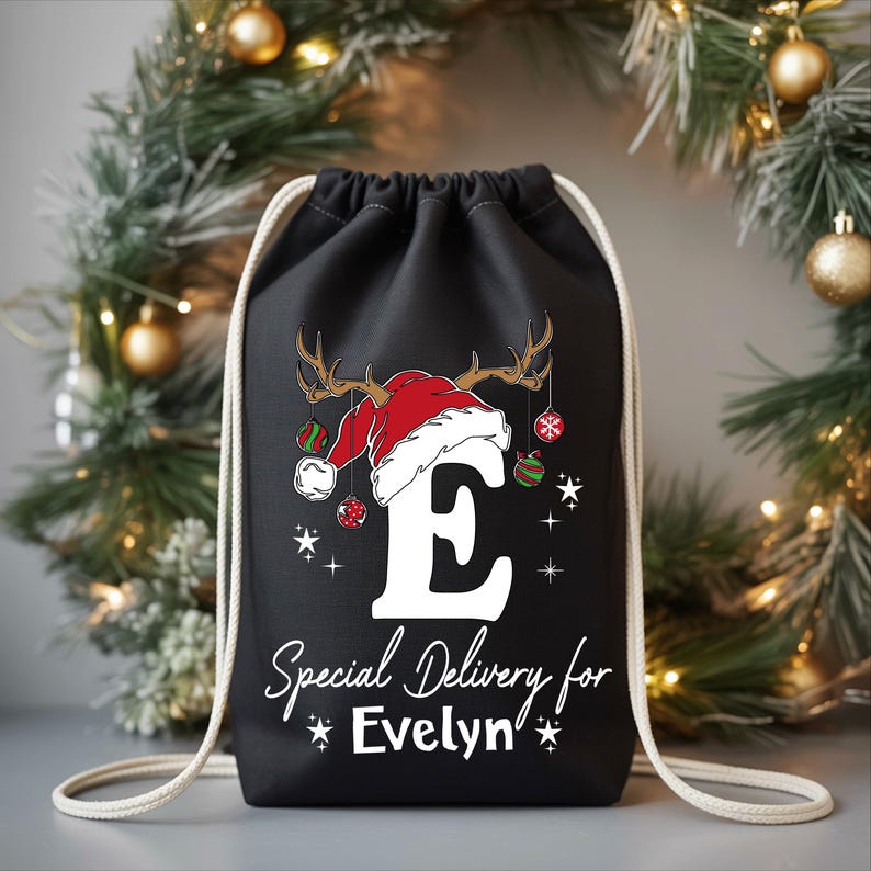 A black drawstring bag with a Christmas-themed design, featuring a Santa hat and ornaments, and the text "Special Delivery for Evelyn" printed on it.