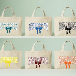 six beige tote bags with the word "STARS" printed on them, each with a different color bow.