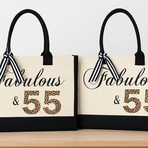 Two beige tote bags with black handles and ribbons, each with the text "Fabulous & 55" printed on them.