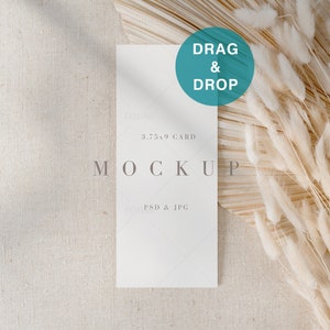 May include: A white card mockup with the text "3.75 x 9 CARD" and "MOCKUP" in gray text. The card is on a beige linen background with a dried pampas grass arrangement to the right.