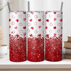 May include: Three stainless steel tumblers with a white background and a red glitter design. The tumblers are decorated with a pattern of red and pink hearts.