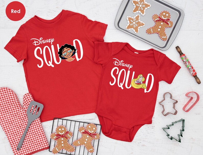 May include: Red Disney Squad t-shirts and onesie. The t-shirt features a graphic of a character with glasses, and the onesie has a princess graphic. Baking supplies and gingerbread cookies are also in the image.