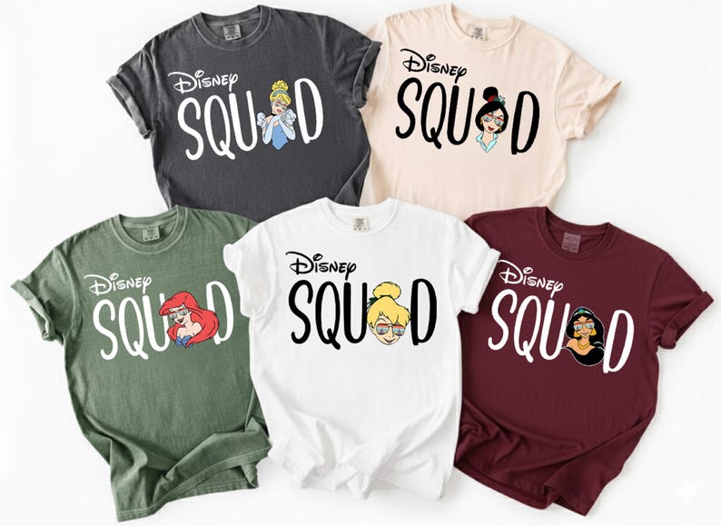May include: Five different colored t-shirts with the text "Disney Squad" and Disney character illustrations. The shirts are in charcoal, beige, green, white, and burgundy. Each shirt features a different Disney princess.
