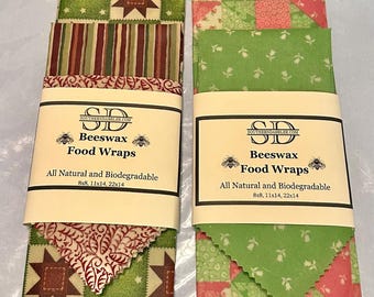 May include: Two sets of beeswax food wraps in various patterns. The wraps are made of fabric and are available in three sizes: 8x8, 11x14, and 22x14 inches. The wraps are all natural and biodegradable.