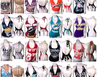 May include: A collection of 24 halter tops made from repurposed band t-shirts. The tops are in various colors and feature different band logos and designs, including Green Day, Metallica, The Eagles, and the Rolling Stones.