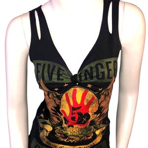 Könnte beinhalten: Ein schwarzes ärmelloses Tanktop mit Cut-Outs an den Schultern und tiefem V-Ausschnitt. Die Vorderseite zeigt einen Grafikdruck mit einem roten Handabdruck über einem Totenkopf, orangefarbenen Flügeln und dem Text Five Finger Death Punch und Sin City, Nevada.