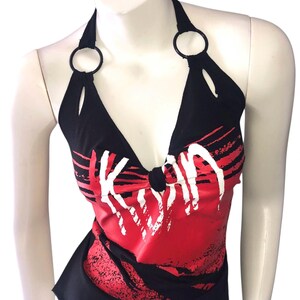 May include: Black halter top with a red and white graphic design. The top has a V-neck and black rings at the halter straps. The word "KISS" is printed in white across the front.
