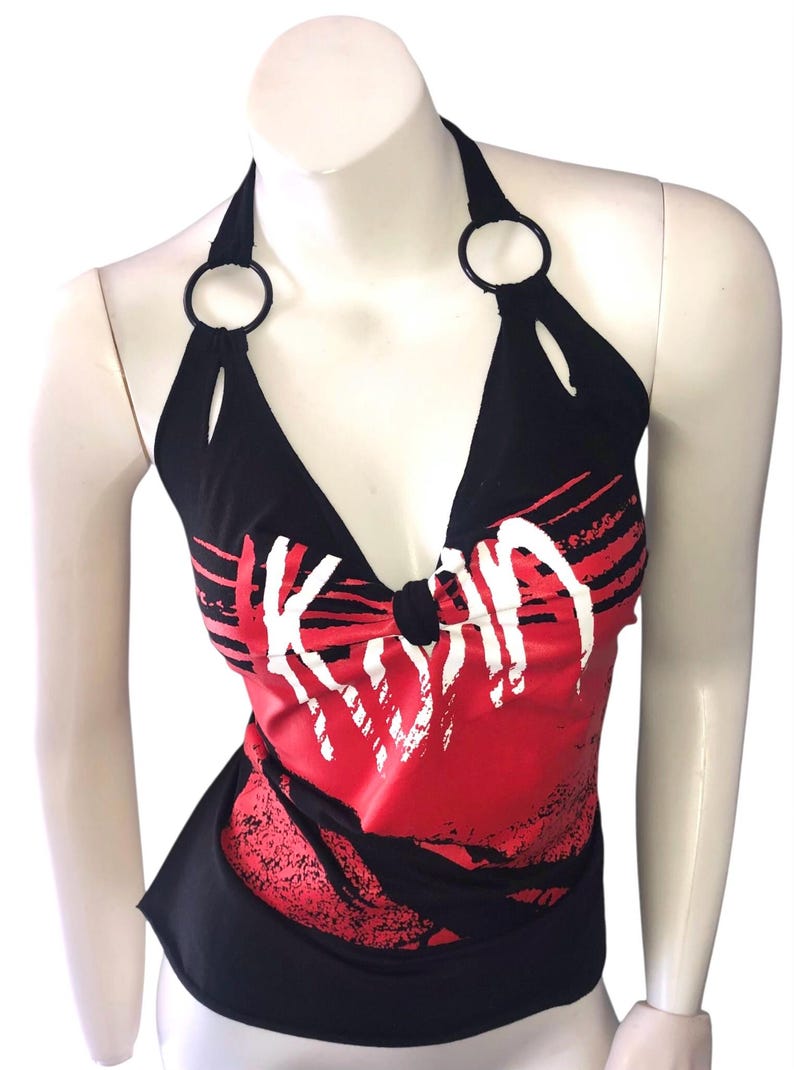May include: Black halter top with a red and white graphic design. The top has a V-neck and black rings at the halter straps. The word "KISS" is printed in white across the front.