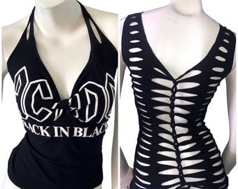 May include: A black halter top featuring the white text AC/DC and BACK IN BLACK on the front. The back of the top displays a series of horizontal cutouts woven together in a vertical column, creating a lattice pattern across the entire back panel.