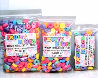 May include: Three bags of colorful soy wax melts shaped like cereal rings. The bags are labeled "Fruity Rings" and say "Soy Wax Melts/Candle Fills" and "Do Not Eat". The bags are 9 oz, 6 oz, and 5 oz.