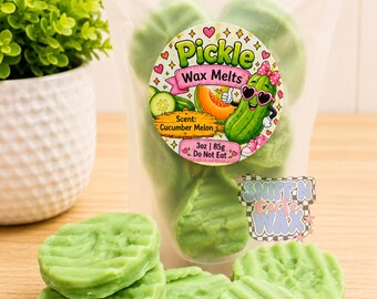 May include: A clear plastic pouch filled with light green, round, textured wax melts. The label features a cartoon pickle wearing pink sunglasses and a bow, with the text Pickle Wax Melts, Scent: Cucumber Melon, 3oz | 85g, Do Not Eat.