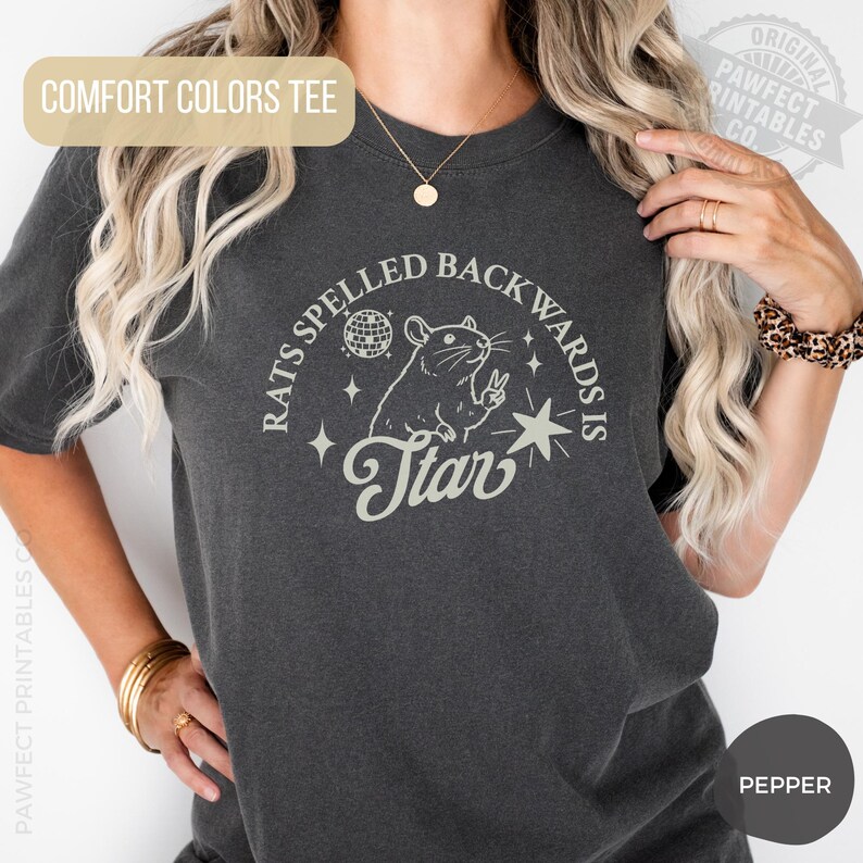 May include: Dark grey Comfort Colors tee with a graphic that reads "Rats Spelled Backwards Is Star". The design features a rat, a disco ball, and a star. The shirt is a Pepper color.