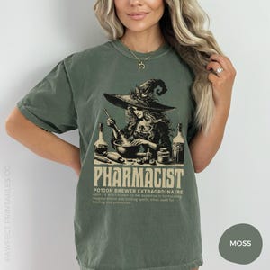 May include: A green t-shirt with a graphic of a witch brewing a potion in a cauldron. The text on the shirt reads "Pharmacist Potion Brewer Extraordinaire noun | A witch known for her expertise in formulating magical elixirs and binding spells, often used for healing and protection."