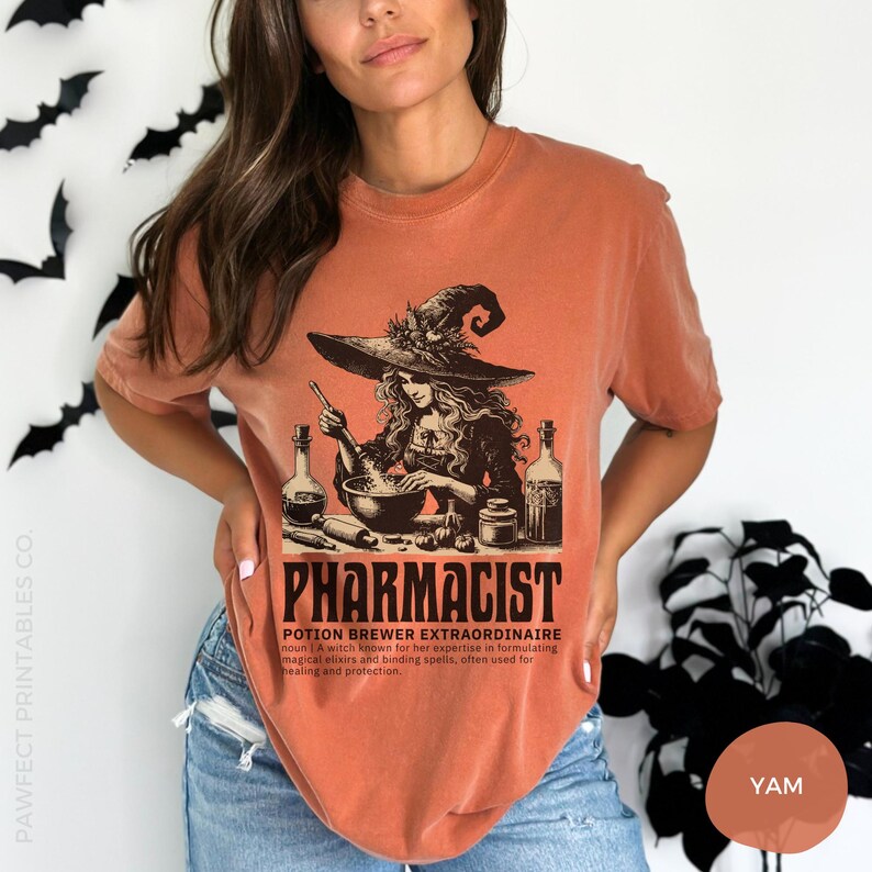 May include: A burnt orange t-shirt with a graphic of a witch brewing a potion in a cauldron. The text "Pharmacist Potion Brewer Extraordinaire" is printed below the graphic. The definition of the term is also included on the shirt.
