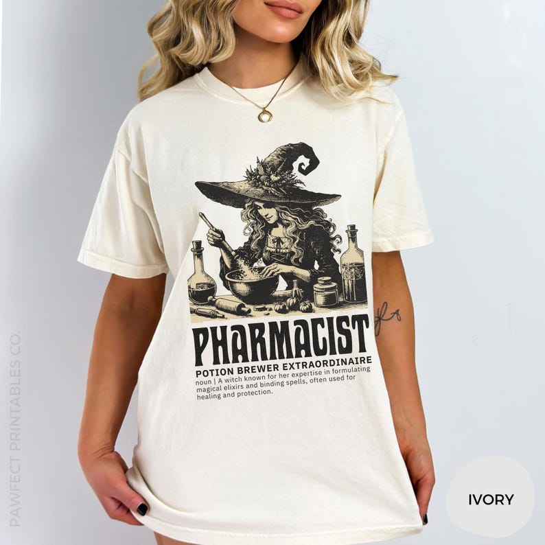 May include: A white t-shirt with a black and white illustration of a witch brewing a potion. The text "Pharmacist Potion Brewer Extraordinaire" is printed below the illustration. The text defines the term as a witch known for her expertise in formulating magical elixirs and binding spells, often used for healing and protection.