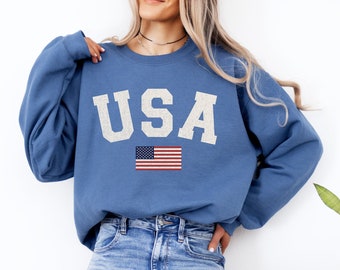 May include: A blue sweatshirt with the word "USA" printed in white with a small American flag underneath.