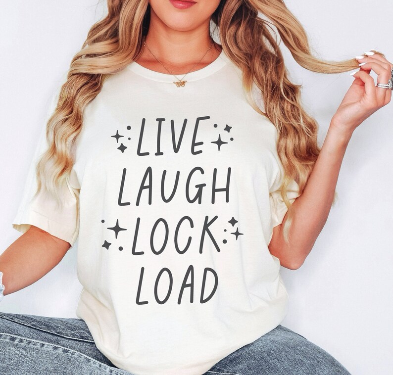 May include: A white t-shirt with the text "LIVE LAUGH LOCK LOAD" printed in black. The text is surrounded by small stars.