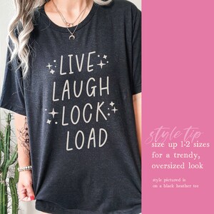 May include: Black t-shirt with white text that reads "LIVE LAUGH LOCK LOAD" with stars around the words. Style tip: size up 1-2 sizes for a trendy, oversized look. Style pictured is on a black heather tee.