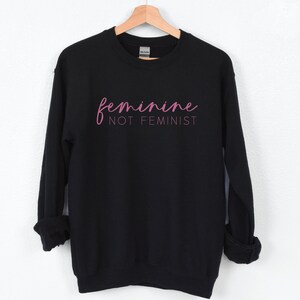 K&ouml;nnte beinhalten: Schwarzer Pullover mit rosa Schriftzug "feminine not feminist".